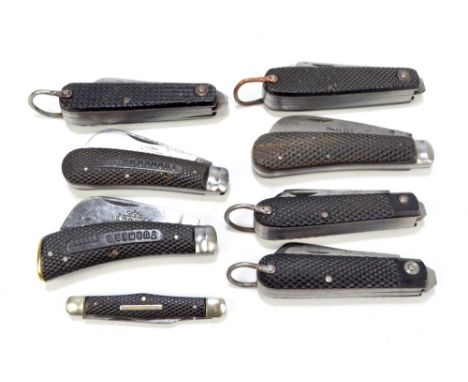 A collection of eight checkered black bodies pocket knives, four near identical examples with ring loop attachment and twin b