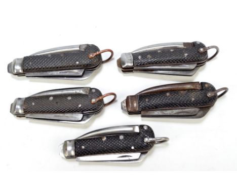 Five military issue clasp knives with checkered black bodies, hinged spike and two blades, each with ring loop attachment, le