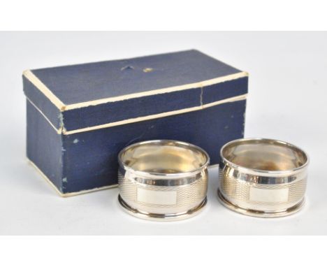 HARMAN BROTHERS; a pair of boxed Elizabeth II hallmarked silver circular napkin rings with engine turned decoration, Birmingh