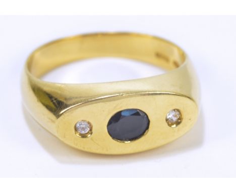 An 18ct yellow gold gentleman's signet ring set with oval cut sapphire and flanked by two round cut clear stones, size S 1/2,