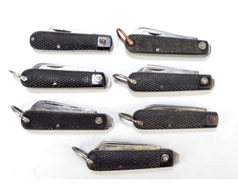 Seven similar checkered black bodied twin bladed pocket knives, six with ring loop attachments (7).