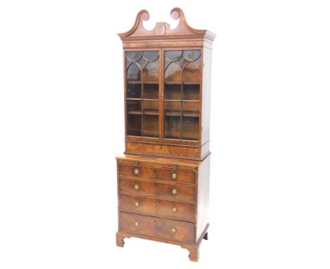 A George III mahogany bookcase, the top with swan neck pediment and dentil frieze, above two astragal glazed doors enclosing 