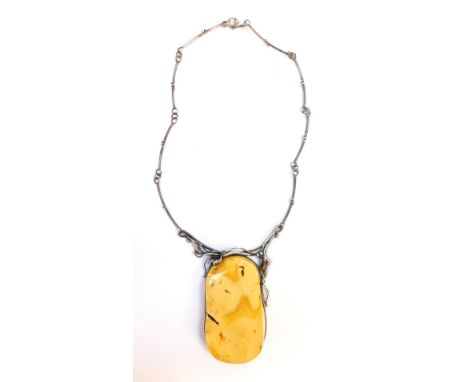 An amber necklace, the oblong raised opal panel in a white metal border, with lily and leaf scroll detailing, on a beaded nec