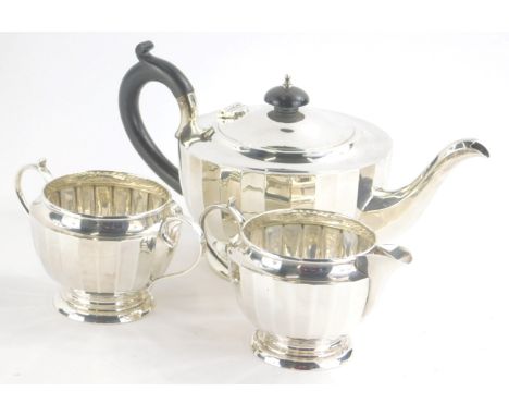 A George VI silver three piece tea service, of ribbed form comprising compressed circular teapot with ebonised handle and kno