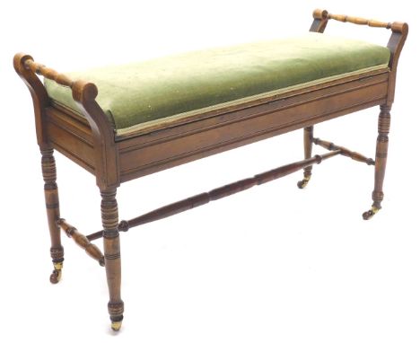 An Edwardian walnut duet stool, with turned scroll cared handles, the green padded hinged seat on turned legs with ceramic ca
