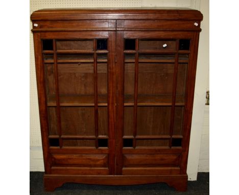 A 20th century teak bookcase with caddy top over a pair of glazed doors with stained corner panels enclosing adjustable shelv