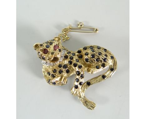 A 9ct yellow gold gem set leopard brooch, the body set with tiny sapphires and the eyes ruby set, hallmarked Birmingham 375 (