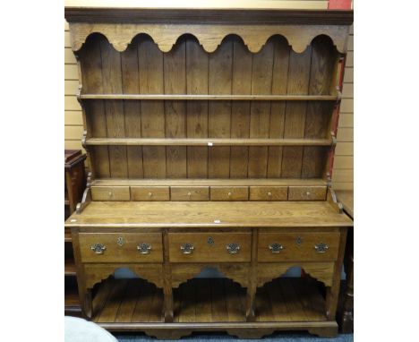 A good reproduction Welsh-type dresser having a planked floor-level platform base, three deep drawers and boarded rack with s