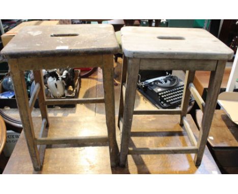 A pair of vintage laboratory stools with centre hand hold
