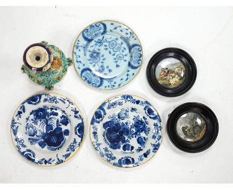 A group of 18th century delftware plates, Wedgwood majolica candlestand (a.f.) and two Victorian framed pot lids
