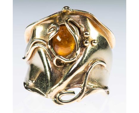 AN AMBER DRESS RING an oval amber within a large and amorphous bezel with beaded and scroll detail. Unmarked, ring size P1/2,