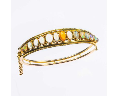 AN EARLY 20TH CENTURY OPAL HINGE OPENING BANGLE graduated oval opals between rope borders, to a double-row hinge opening bang