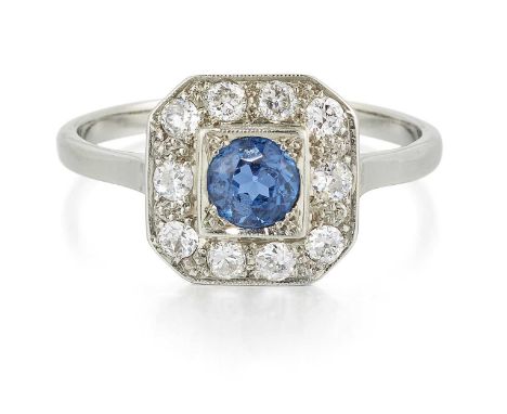 AN EARLY 20TH CENTURY SAPPHIRE AND DIAMOND CLUSTER RING a round-cut sapphire within an octagonal milgrain border of round bri