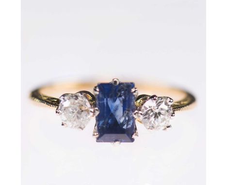 A SAPPHIRE AND DIAMOND THREE STONE RING a baguette-cut sapphire between old-cut diamonds, to foliate engraved knife-edge shou
