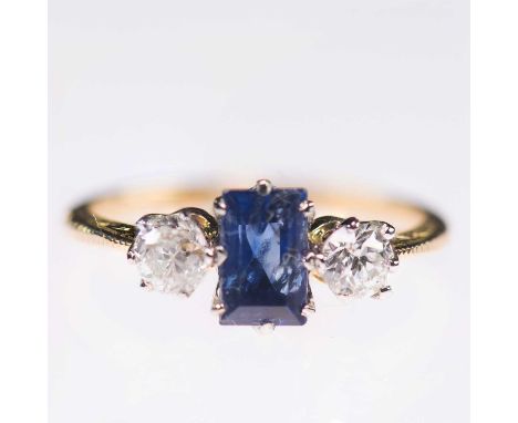 A SAPPHIRE AND DIAMOND THREE STONE RING a baguette-cut sapphire between old-cut diamonds, to foliate engraved knife-edge shou