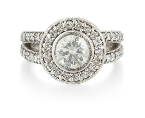 A PLATINUM DIAMOND RING a round brilliant-cut diamond within a milgrain-set diamond border, to diamond-set forked shoulders. 