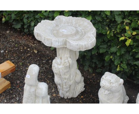 A concrete bird bath on column in the form of a tree trunk