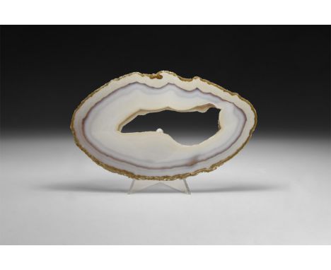 A fine cut and polished agate slice with bands of white, blue and orange; large central cavity framed by small quartz crystal