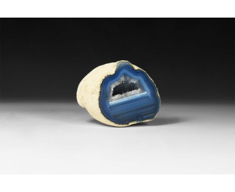 A fine cut and polished agate geode half with bands of blue and white colour, central void filled with clusters of small crys