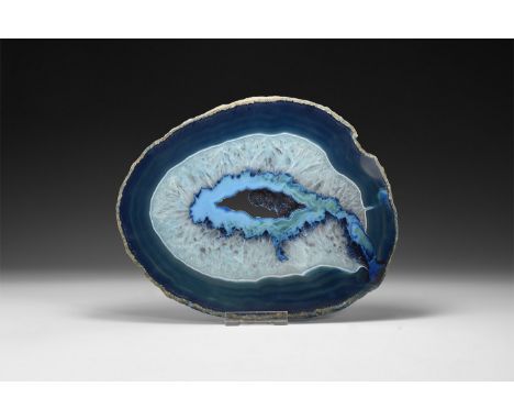 A fine cut and polished agate slice with blue bands and honeycomb crystal formation, central cavity; colour enhanced.  652 gr