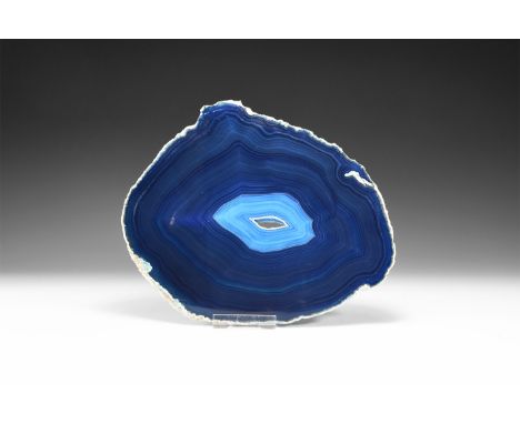 A fine cut and polished agate slice with blue bands and small central cavity with crystal formation, colour enhanced.  544 gr