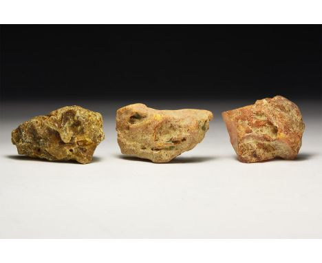 A group of three large orange and yellow natural amber specimens in 'as found' condition, in white card tray.  54 grams total