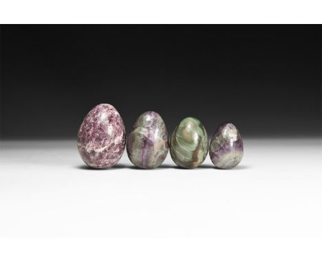 A group of four polished eggs comprising of two fluorite, one green agate and one purple agate; in white card tray.  209 gram