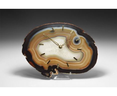 A large agate slice with bands of blue, orange and brown, small cluster of quartz crystals to the centre; brass hour hands to