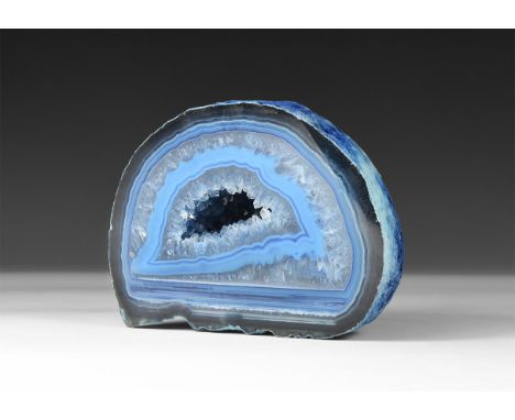 A fine cut and polished geode half with bands of blue agate and honeycomb crystals; central cavity filled with miniature crys