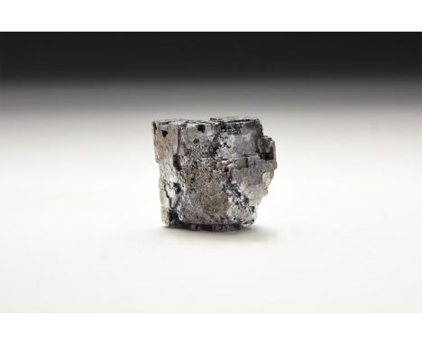 A specimen of galena with interlocking and stepped cube-shaped crystals, in white card tray with label reading: 'Galena, Tri-