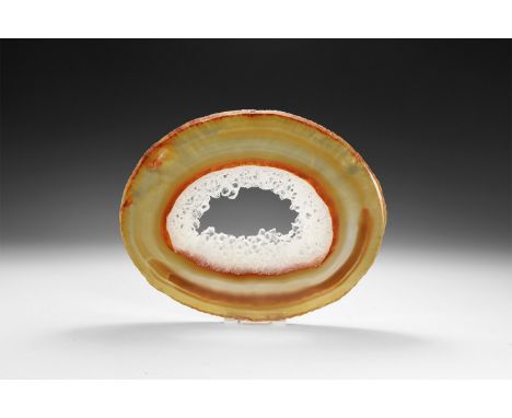 A fine cut and polished agate slice with brown and yellow bands, honeycomb crystal formation around central cavity, colour en