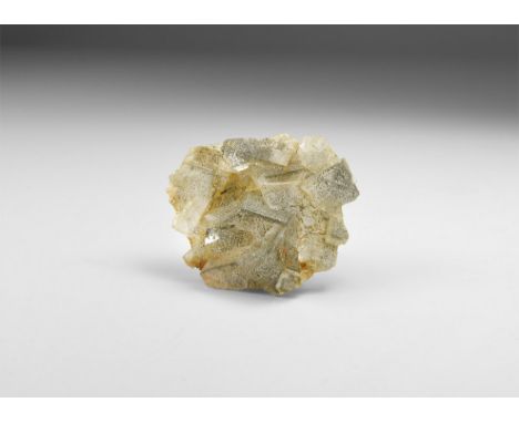 A group of fine cubic translucent fluorite crystals with hematite 'flakes', in white card tray with label reading: 'FLUORITE 