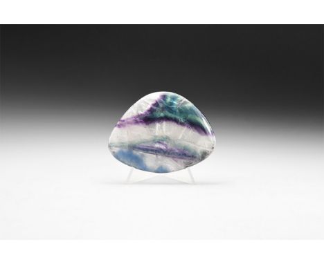 An oval polished specimen of fluorite, with purple and green colour; natural fractures to the body with 'rainbow' reflection.