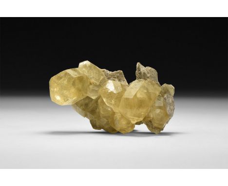 A fine specimen of dark yellow calcite crystals on a matrix, in white card tray with label reading: 'Calcite, Tri-State (Mill