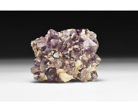 A fine specimen of purple and white amethyst crystals, in a white card tray with label reading: 'Amethyst, Antigas, Uraguay'.
