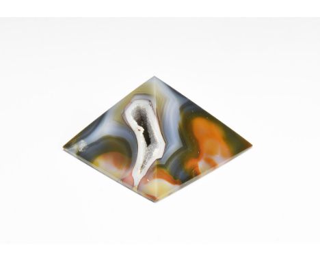 A pyramid cut in banded brown and blue agate, with highly polished faces and base and void filled with quartz crystals, in wh