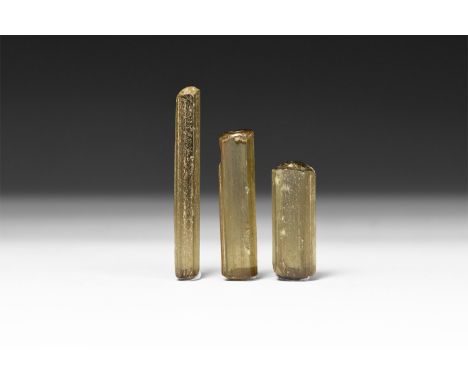 A group of three deep yellow tourmaline crystals, in white card tray with label reading: 'Tourmaline, Minas Gerais, Brazil''.