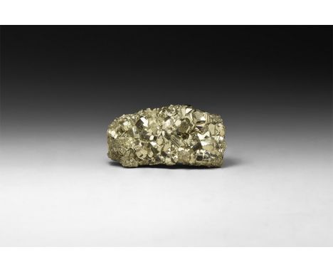 A group of lustrous pyrite crystals formed principally as pyritohedrons, in white card tray with label reading: 'Pyrite, Huan