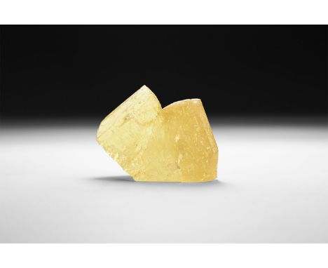 A fine specimen of two yellow joined triangular calcite crystals, in white card tray with label reading: 'Calcite Twin, Tri-S