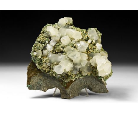 A sheet of calcite crystals on a rock groundmass, from Maharachita, India, with unusual step growth barrel forms. See Bonewit