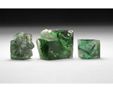 A group of three green fluorite crystals in a card tray with label stating 'Green Fluorite / Rogerley Mine / Frosterley, Wear