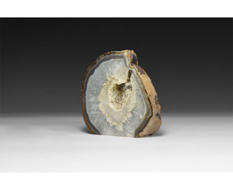 A fine cut and polished section of a geode with bands of blue and white agate, honeycomb crystals sections surrounding the ce