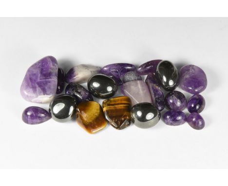 A group of eighteen cut and polished amethyst specimens, some cabochon; two tiger's eye, and four hematite, in white card tra
