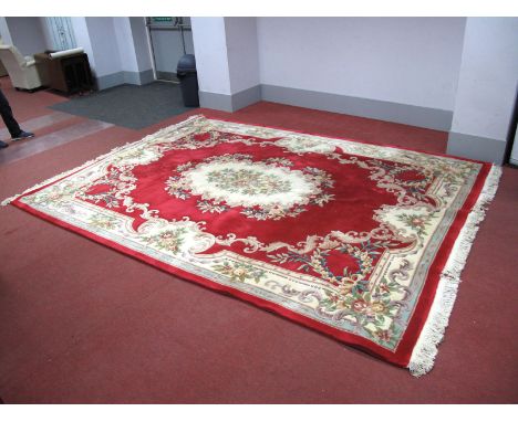 A Chinese Wool Tassled Carpet, with cream central motif, all-over rose and scroll decoration on red ground, 364 x 274cm.