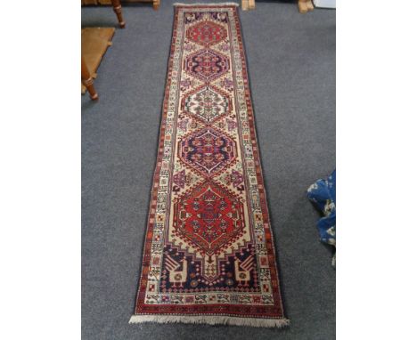 A fringed Persian runner of geometric design.  