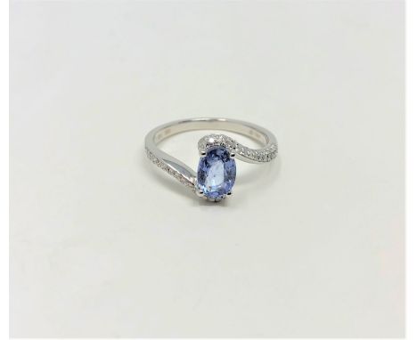 A 14ct white gold sapphire and diamond ring featuring centre oval cut blue sapphire (1.02ct), claw set with sixty-four round 