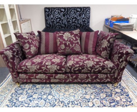 A contemporary settee upholstered in a Burgundy and silver floral fabric with scatter cushions.  