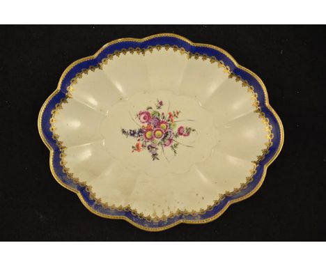 A first period Worcester oval scalloped dish, gilt and blue border, central reserve painted with floral arrangement, open cre