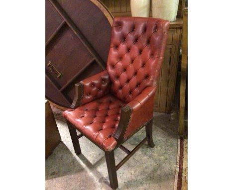 A 1930s/40s library armchair with button back, arms and seat, upholstered in red leatherette style material, on moulded strai