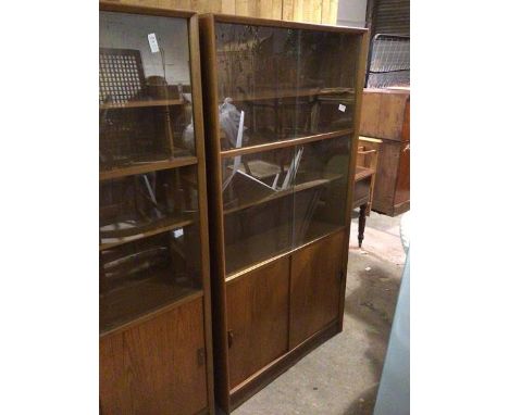 A mid century teak tall wall unit, fitted sliding glass doors enclosing interior fitted four shelves, above sliding panel doo